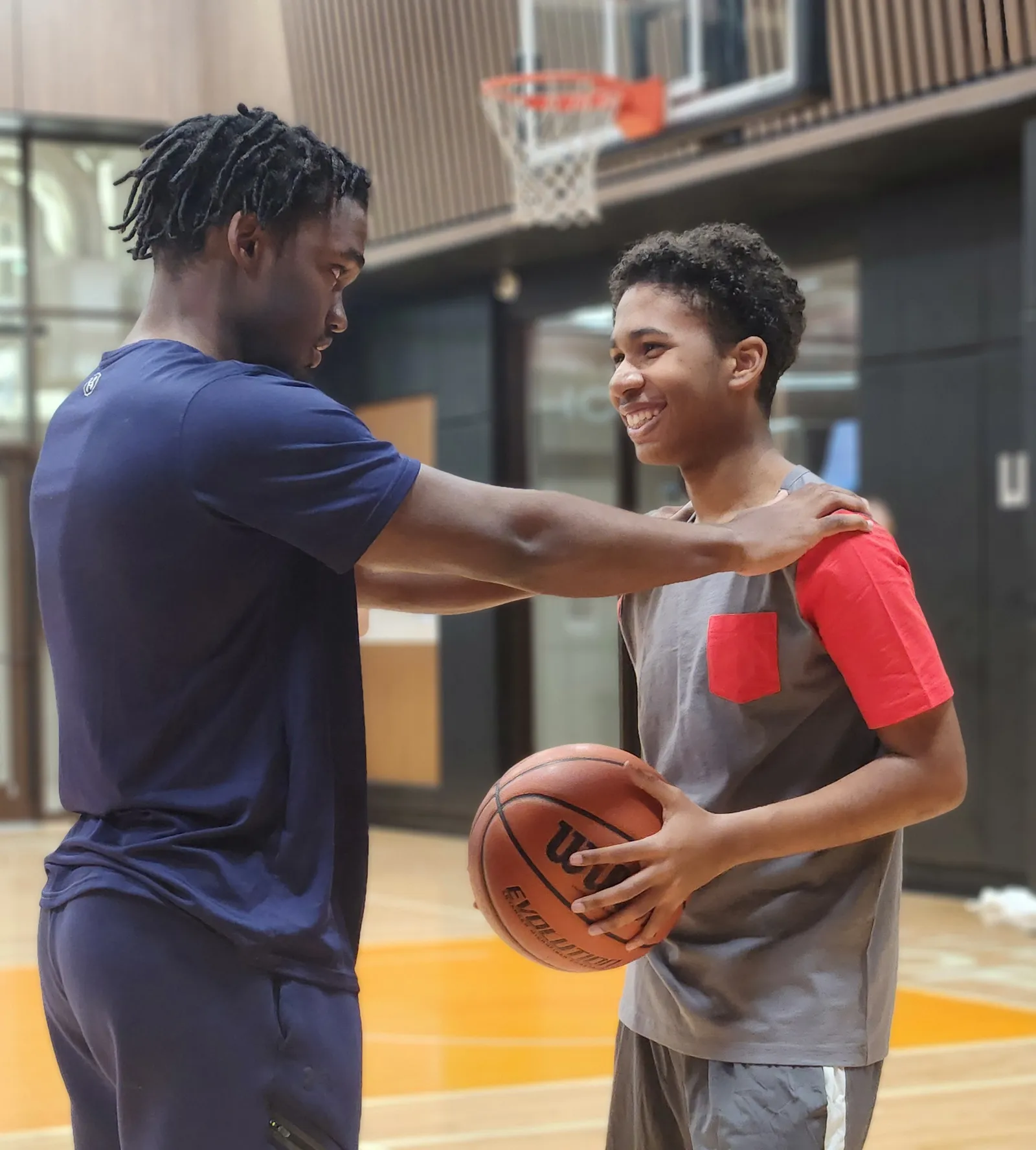 Man speaking with a young man holding a basketball