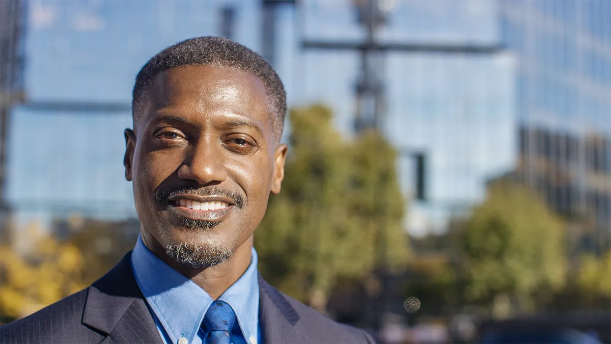 Black man in a suit smiling outdoors
