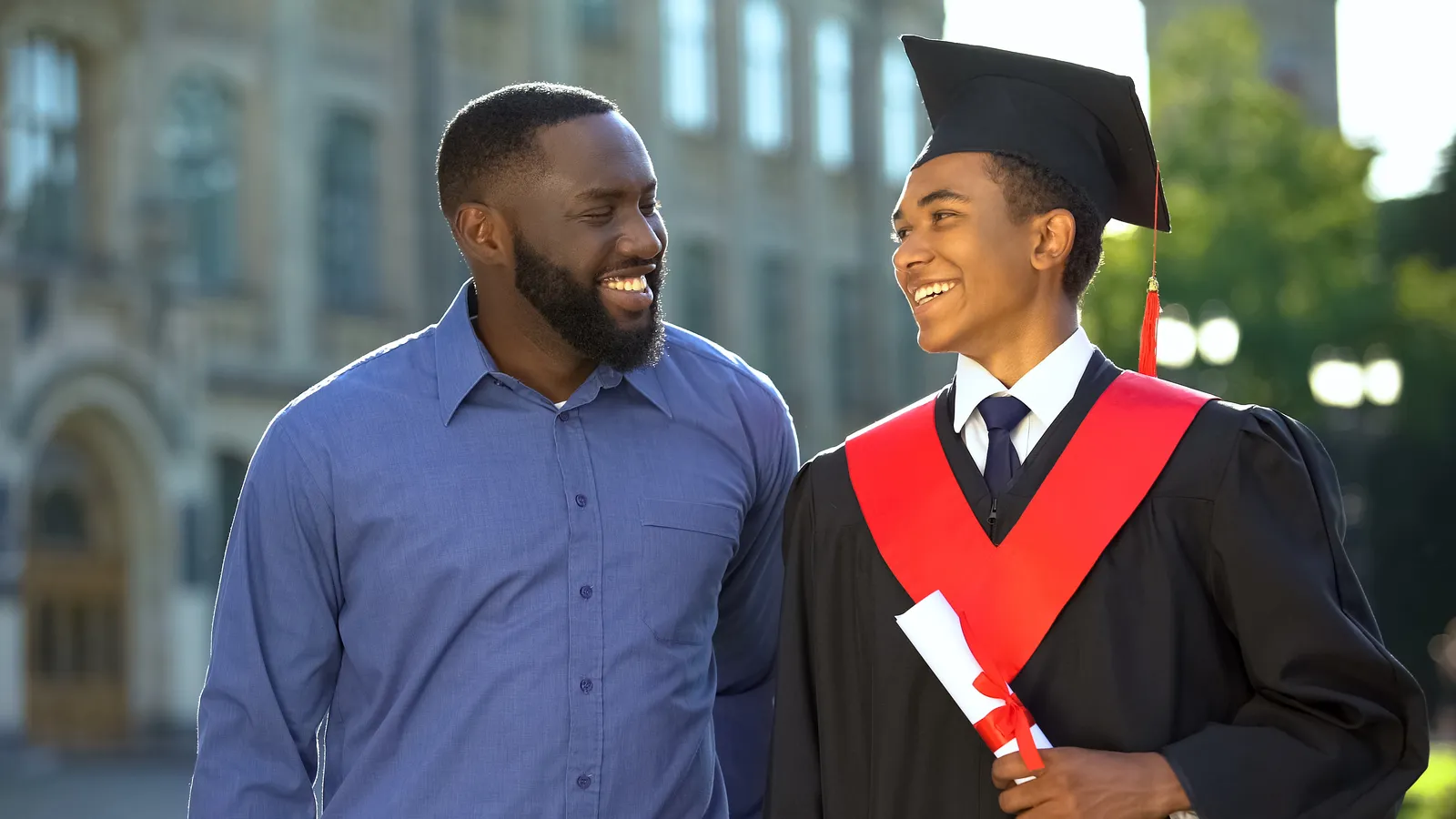 Black man talking with a young graduate in a cap and gown