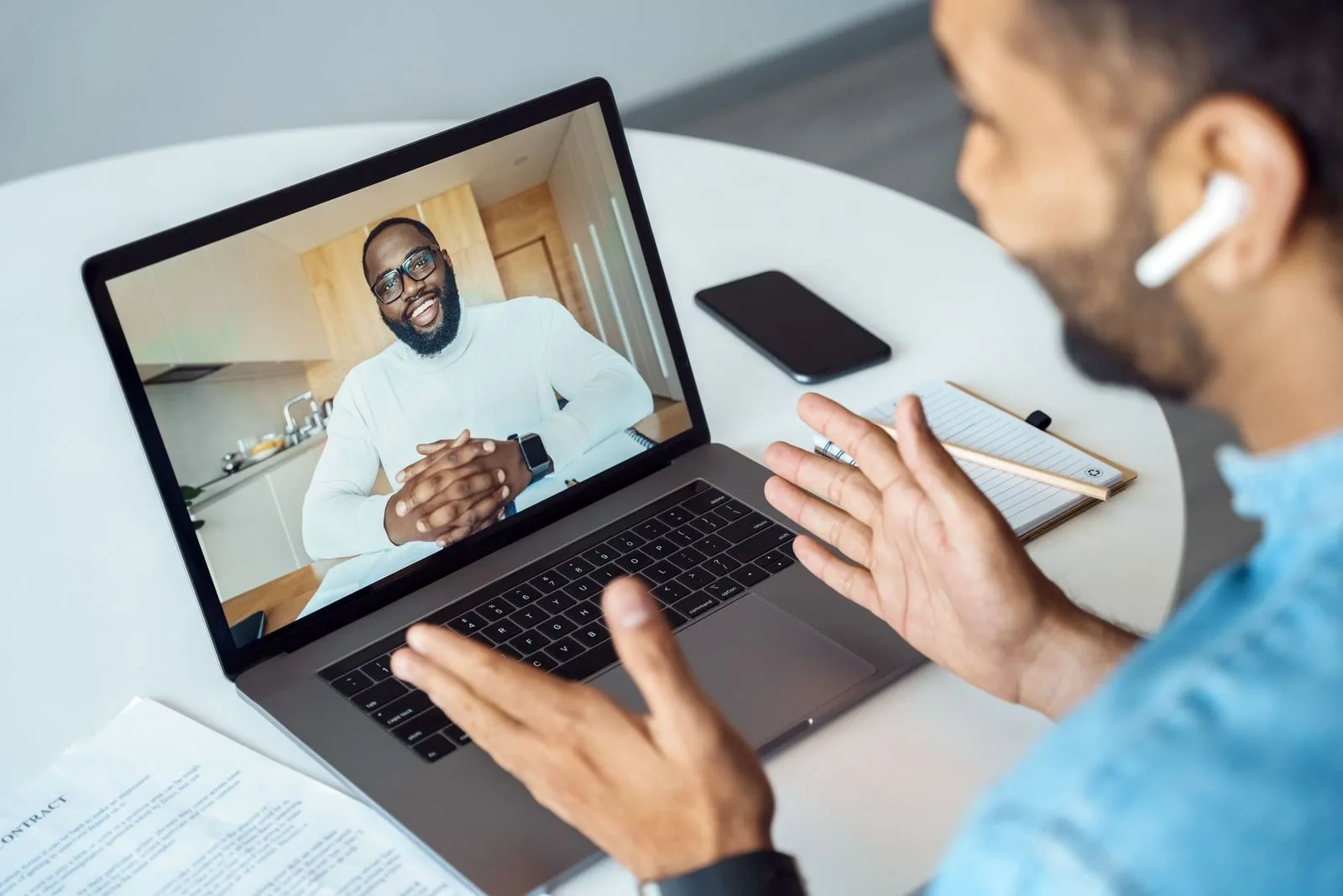 Man speaking with a Black man on a laptop video call