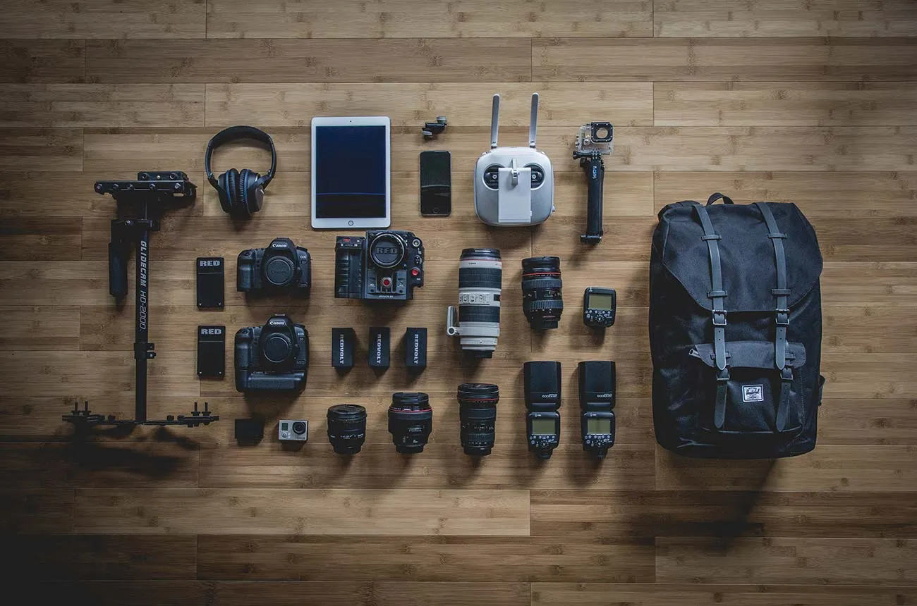 Camera equipment and travel accessories arranged on a wooden surface